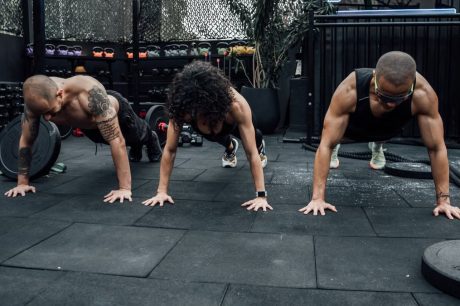 Three individuals performing push-ups together in a Mexico City gym setting.
